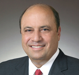A middle-aged man in a suit and red tie smiles at the camera against a plain, gradient background, embodying the professionalism of lawyers in Chicago specializing in litigation support.