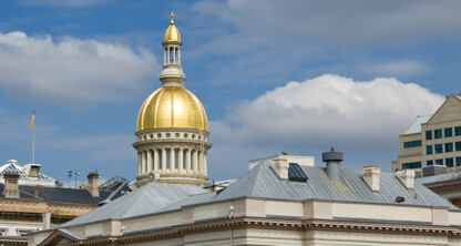 The image shows the gold-domed New Jersey State House building under a partly cloudy sky, with surrounding rooftops in the foreground—far from where top lawyers in Chicago or major law offices typically conduct their business.
