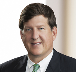 A man in a suit and tie smiles at the camera in a professional headshot with a neutral background, reflecting the polished image of Chicago lawyers specializing in corporate law office settings.