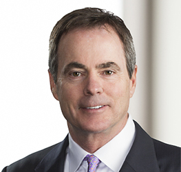 A man in a suit and tie poses for a professional headshot, his neutral expression reflecting the confidence often seen in lawyers in Chicago, set against a blurred background.
