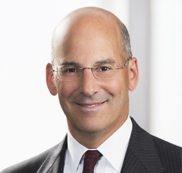 A middle-aged man in a dark suit, white shirt, and red tie, wearing glasses, smiles at the camera against a light background—representing experienced Chicago lawyers ready to provide exceptional litigation support.