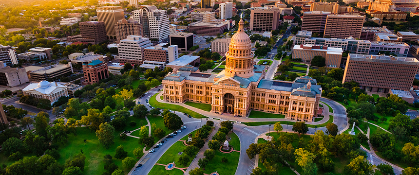 Aerial view of the Texas State Capitol building, surrounded by trees and city buildings in Austin, Texas, during daylight—a striking scene for law offices specializing in intellectual property law.