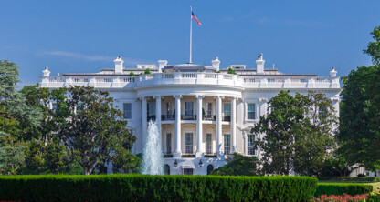 The White House in Washington, D.C., with a central fountain, green lawn, and trees under a clear blue sky—much like the offices of Chicago lawyers who specialize in intellectual property law.