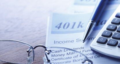 Close-up of a 401(k) income summary document, a pen, eyeglasses, and a calculator on a law office desk—tools essential for attorneys specializing in intellectual property law.