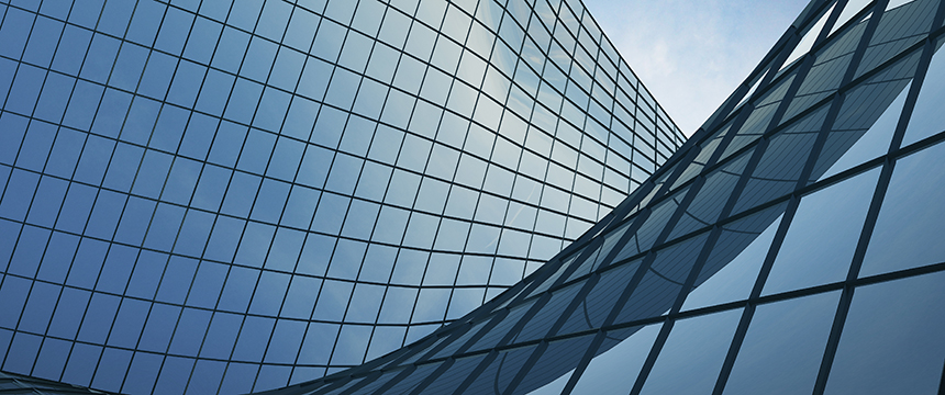 Curved glass facade of a modern building reflecting the sky, with grid-like window patterns and a blue tint—an impressive setting for prestigious law offices specializing in intellectual property law.