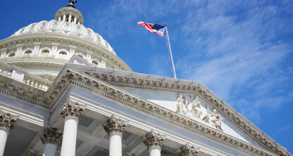 The United States Capitol building with columns and a dome, topped by an American flag against a blue sky—an inspiring symbol for law offices and those seeking litigation support.