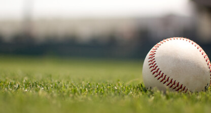 A baseball rests on green grass with a blurred background, reminiscent of a calm break outside bustling Chicago lawyers' law offices.