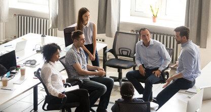 Six people sit in a circle having a discussion in a modern law office with desks, chairs, and natural light from the windows—an ideal setting for lawyers in Chicago collaborating on intellectual property law matters.