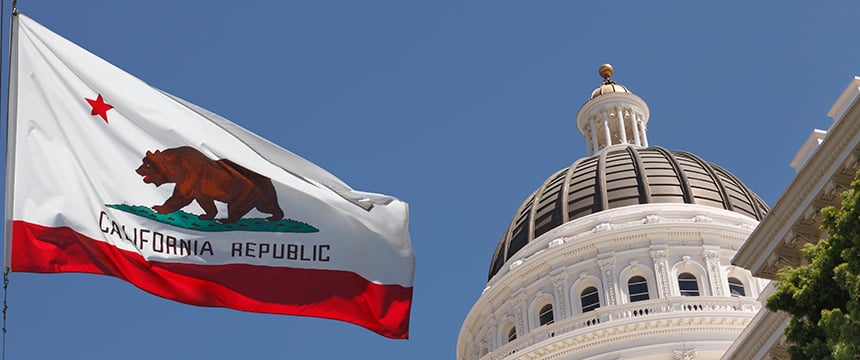 The California state flag waves in front of the California State Capitol building under a clear blue sky, embodying the spirit upheld by any leading corporate law office.