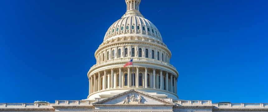 The United States Capitol dome against a clear blue sky, with an American flag flying in front of the building—an inspiring sight for law offices and those seeking litigation support across the nation.