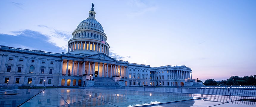 The U.S. Capitol building at dusk, with lights glowing inside, reflects on a glass surface in the foreground—much like the polished professionalism of a corporate law office or lawyers in Chicago offering litigation support.