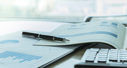 Pen resting on an open financial report with charts and graphs, calculator nearby on a desk in a bright corporate law office, capturing the meticulous work of Chicago lawyers.