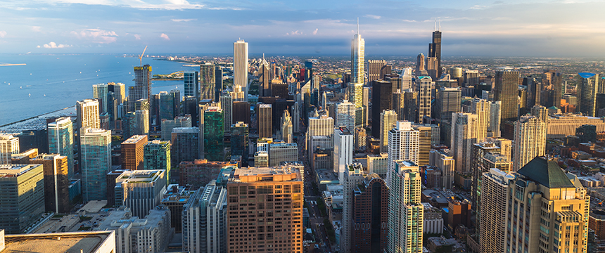 Aerial view of downtown Chicago with tall skyscrapers, law offices clustered throughout the city, Lake Michigan in the background, and partly cloudy skies.