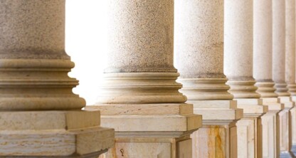 Row of stone columns with detailed bases and shafts, forming a colonnade in a classical architectural style, often seen at law offices or courthouses providing litigation support to lawyers in Chicago.