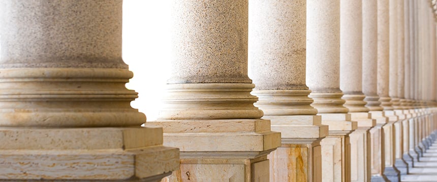 Row of stone columns with detailed bases and shafts, forming a colonnade in a classical architectural style, often seen at law offices or courthouses providing litigation support to lawyers in Chicago.