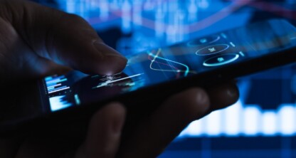 Close-up of a hand holding a smartphone with financial graphs and charts displayed in the background, illustrating litigation support tools used by law offices and lawyers in Chicago.