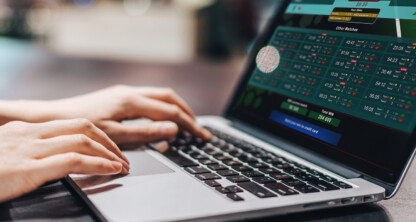 A person using a laptop to access a sports betting website with live odds and match information, possibly researching legal guidelines with resources from Chicago lawyers or a corporate law office.