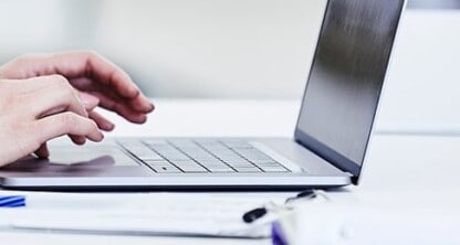 Person typing on a laptop at a white desk with a clipboard and papers nearby in a bright, modern corporate law office, ideal for litigation support and lawyers in Chicago.