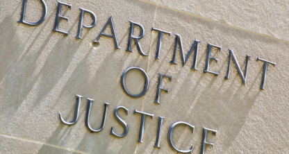 The words "Department of Justice" are engraved in capital letters on a light-colored stone wall, symbolizing the authority that guides lawyers in Chicago and those seeking litigation support.