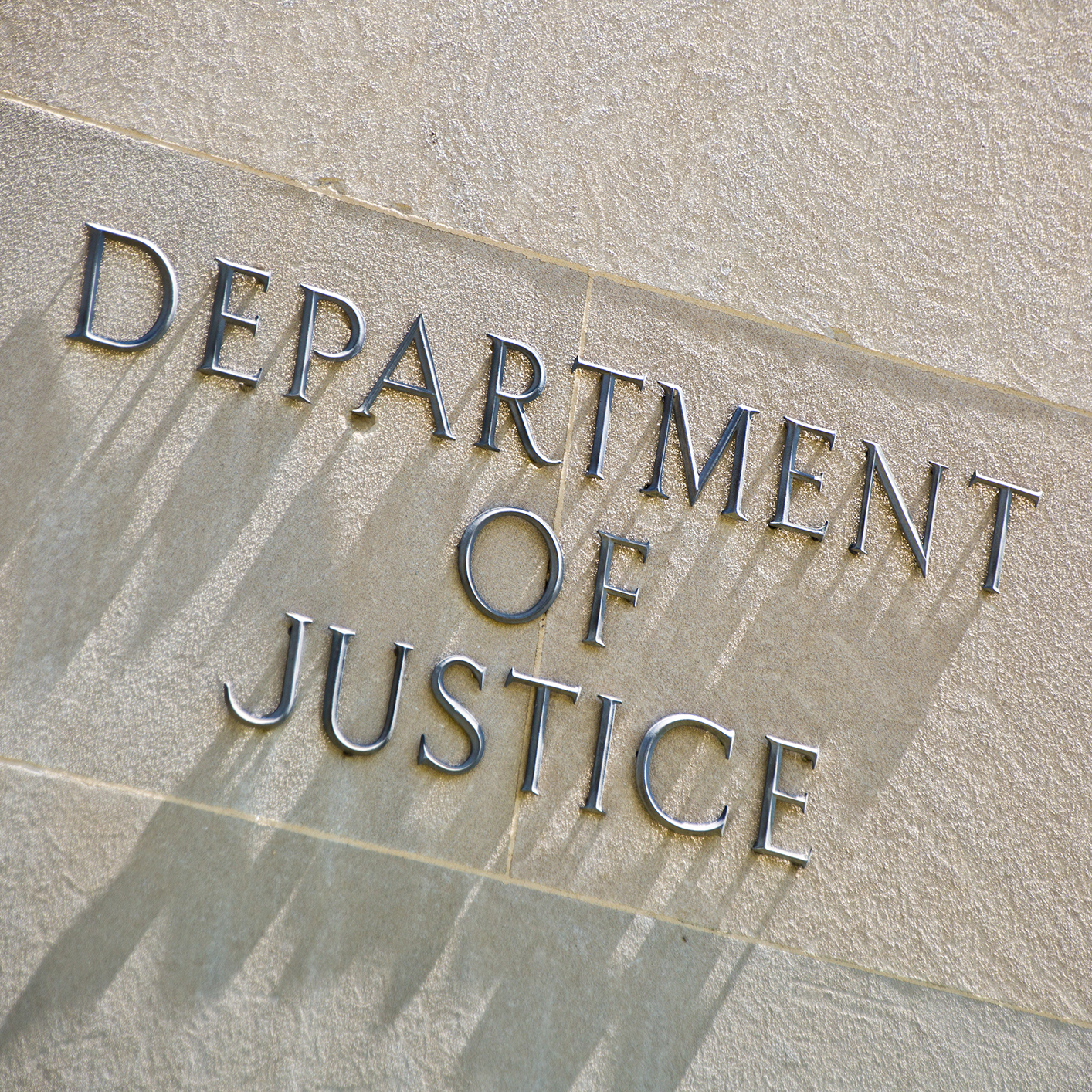The words "Department of Justice" are engraved in capital letters on a light-colored stone wall, symbolizing the authority that guides lawyers in Chicago and those seeking litigation support.