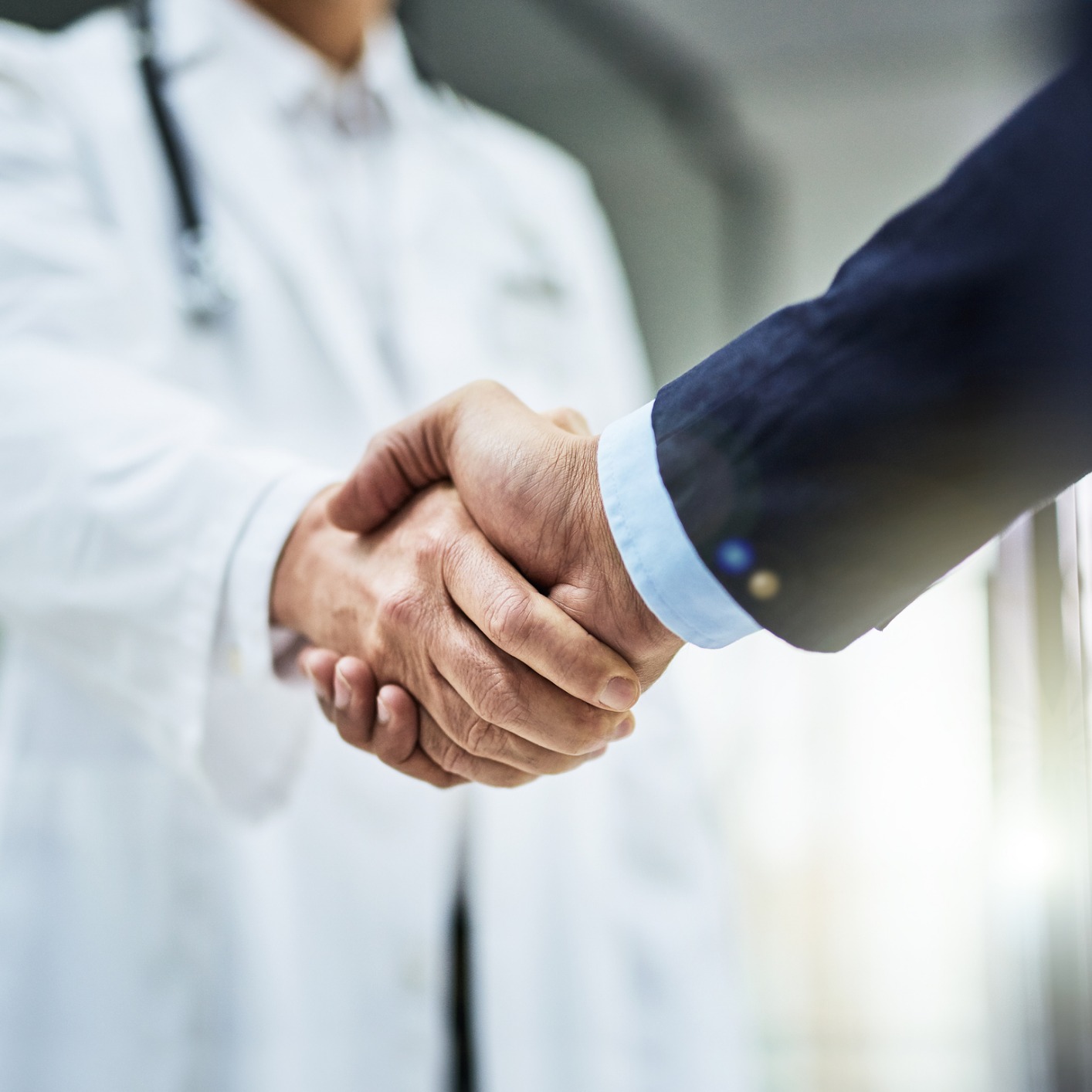 A doctor in a white coat and stethoscope shakes hands with a person in a suit, illustrating a professional partnership between healthcare experts and chicago lawyers for litigation support.