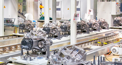 Automotive components on an assembly line in a modern factory, surrounded by machinery and industrial equipment—a scene where intellectual property law protects innovative designs and processes.