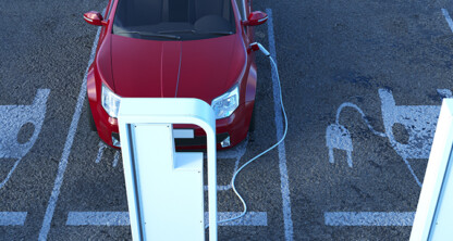 A red electric car is parked in a designated charging spot outside law offices, plugged into an electric vehicle charging station in the parking lot.