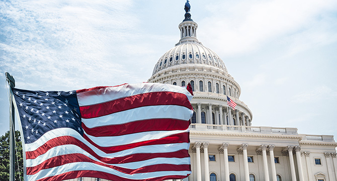 The American flag waves in front of the United States Capitol building under a partly cloudy sky, symbolizing justice and inspiring Chicago lawyers and law offices dedicated to litigation support.