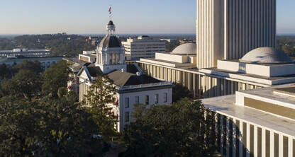 Aerial view of the Florida State Capitol complex in Tallahassee, featuring the historic capitol building with a dome and the modern high-rise capitol tower, resembling the sleek design of major corporate law offices.