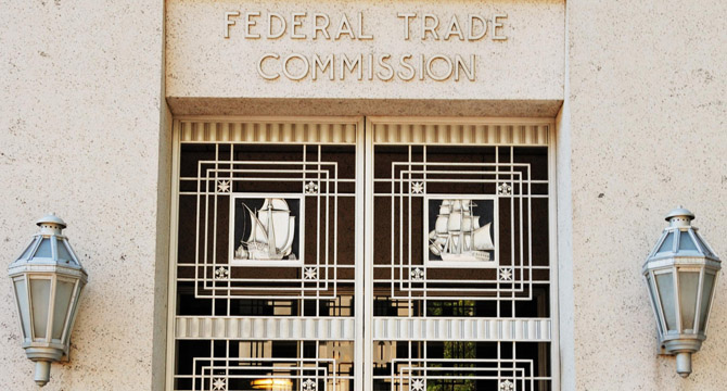 Entrance of the Federal Trade Commission building with decorative metal doors featuring ship designs and two wall lanterns, representing the authority behind intellectual property law.