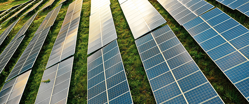 Rows of solar panels installed outdoors on a grassy field, angled to capture sunlight for generating renewable energy—a sustainable initiative often advised by law offices focused on environmental and corporate compliance.