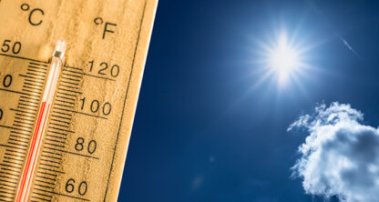 A thermometer showing high temperatures in both Celsius and Fahrenheit stands under a bright sun in a clear blue sky, much like how Chicago lawyers handle litigation support during intense cases.