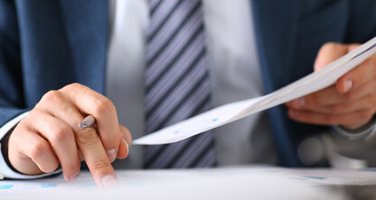 A person in a suit reviews financial documents at a law office, pointing at a chart with one hand while holding papers in the other—reflecting the expertise of Chicago lawyers in complex financial and intellectual property law matters.