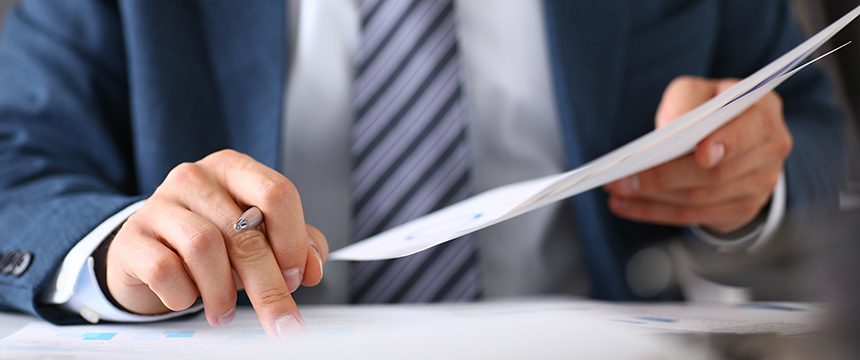 A person in a suit reviews financial documents at a law office, pointing at a chart with one hand while holding papers in the other—reflecting the expertise of Chicago lawyers in complex financial and intellectual property law matters.