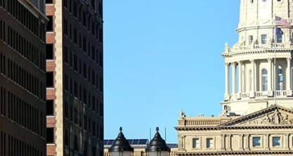 A classical-style government dome rises amid tall modern offices, perhaps home to a leading corporate law office. Autumn trees in the foreground add color to this iconic scene for lawyers in Chicago.