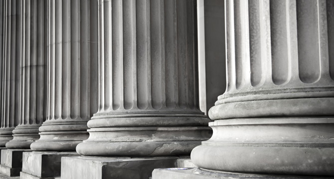 Close-up view of the bases of several large, fluted stone columns, evoking the strength and stability often found in corporate law office architecture.