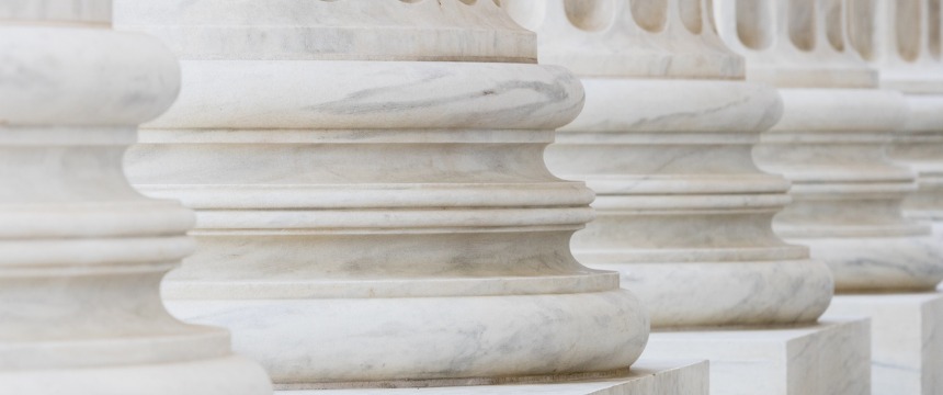 Close-up view of the bases of several white marble columns, often found in prestigious law offices, showing smooth, rounded shapes and subtle veining.