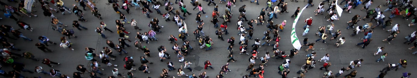 Aerial view of a large crowd of people walking in various directions on a city street, reflecting the dynamic energy found among lawyers in Chicago navigating cases and providing litigation support.