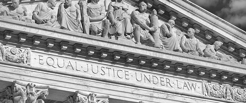 The marble facade of a courthouse, home to a leading corporate law office, features sculptures of figures and the inscription "EQUAL JUSTICE UNDER LAW" engraved below them.