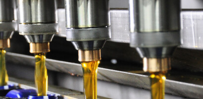 Close-up of multiple automated nozzles dispensing liquid into rows of containers on a production line, similar to the precision found in law offices or among Chicago lawyers specializing in intellectual property law.