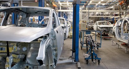 Partially assembled car bodies on an automotive production line in a factory, where efficiency rivals the precision of chicago lawyers offering litigation support. Machinery and equipment are visible throughout the scene.