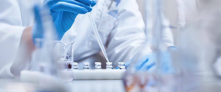 A person wearing blue gloves uses a pipette to transfer liquid into small vials in a laboratory setting, supporting litigation support for lawyers in Chicago through accurate scientific analysis.