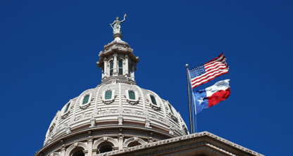 The dome of the Texas State Capitol with the U.S. and Texas flags flying against a clear blue sky—a fitting backdrop for law offices and litigation support professionals serving the heart of Texas.