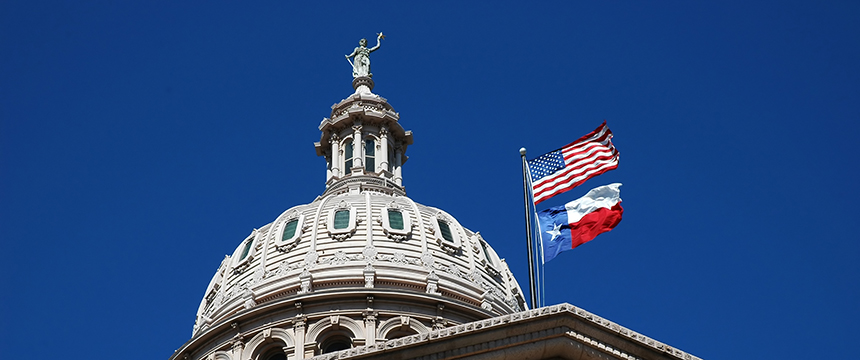 The dome of the Texas State Capitol with the U.S. and Texas flags flying against a clear blue sky—a fitting backdrop for law offices and litigation support professionals serving the heart of Texas.