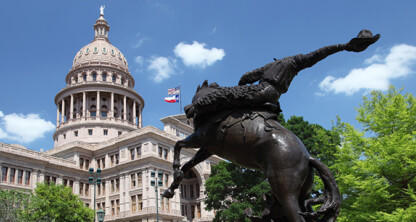 Bronze statue of a horse and rider in front of the Texas State Capitol building under a blue sky with scattered clouds, reminding visitors of landmark sites found near top Chicago lawyers and their offices.