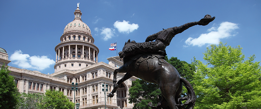 Bronze statue of a horse and rider in front of the Texas State Capitol building under a blue sky with scattered clouds, reminding visitors of landmark sites found near top Chicago lawyers and their offices.