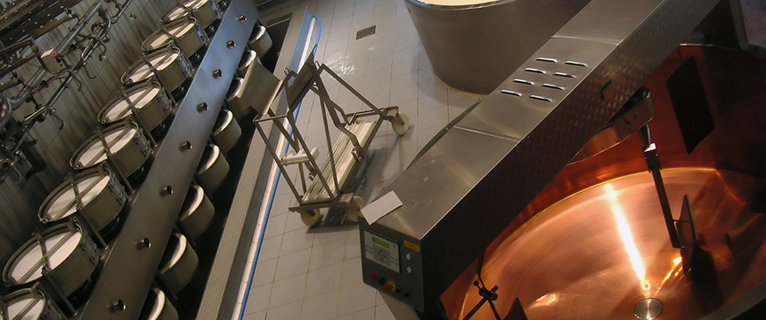 Large stainless steel vats and equipment in a modern dairy or cheese production facility, viewed from above—ideal for businesses seeking guidance from lawyers in Chicago on food safety compliance or intellectual property law.