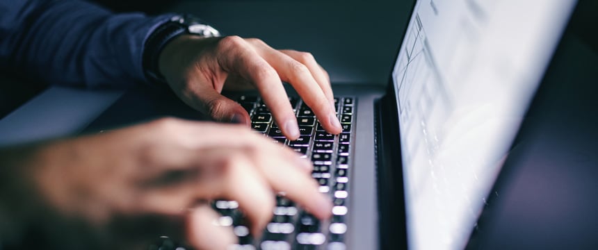 Close-up of hands typing on a laptop keyboard, with a blurred screen in the background—ideal for lawyers in Chicago or law offices handling sensitive intellectual property law cases.