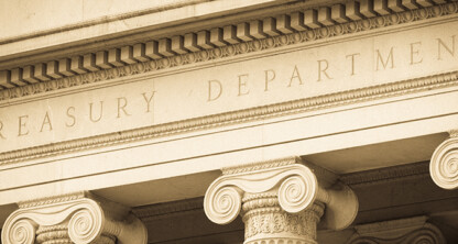 Close-up of the stone facade of a corporate law office with "Treasury Department" engraved above a row of classical columns.