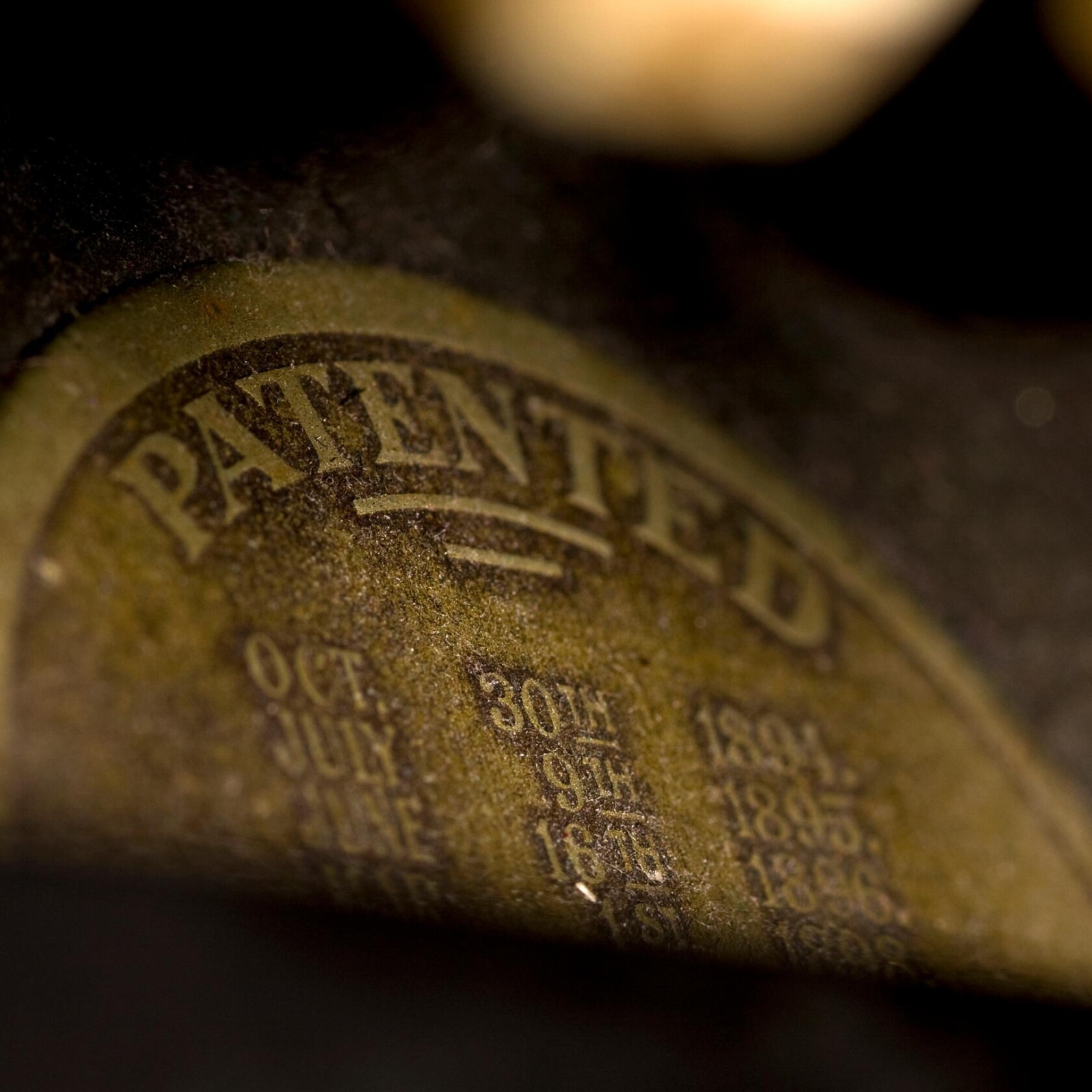 A close-up of a worn, oval-shaped label showing the word “PATENTED” in large letters and a list of dates below it—an artifact that could intrigue chicago lawyers or those seeking litigation support.